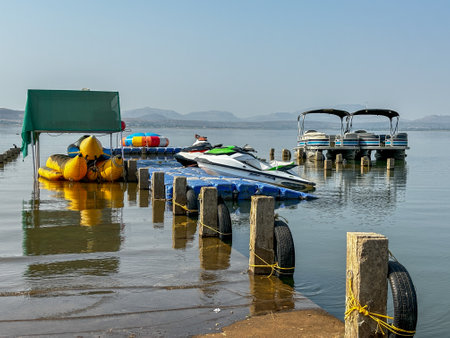 A pontoon boat is docked at a marina. The boat is surrounded by yellow and blue inflatable raftsの写真素材