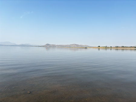 A calm lake with a mountain in the background. The sky is clear and blue. The water is still and peacefulの写真素材