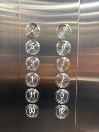 A silver elevator with a red circle on the number 4. The numbers are in black and the buttons are in...