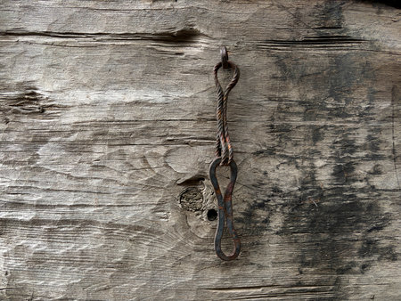 A rusty metal object is sitting on a wooden surface. The object is bent and twisted, and it is a key. The scene has a vintage and rustic feel, with the wooden surface and the oldの写真素材