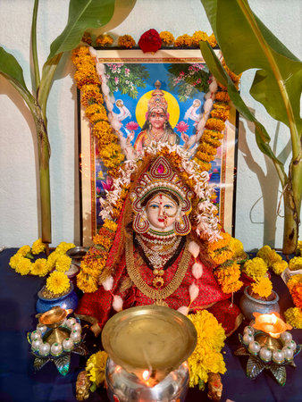 A table is decorated with a variety of items, including a photo of goddess Laxmi on Diwali, candles,...