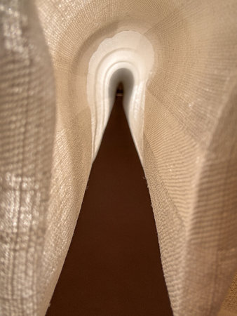 A long, narrow tunnel is covered in white fabric. The tunnel is dark and the fabric is white, creating a stark contrast between the two. The tunnel appears to be emptyの写真素材