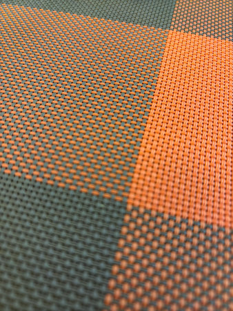 A checkered patterned fabric with orange and green colors. The pattern is made up of small squares and circlesの写真素材