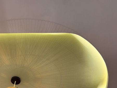 A yellow lampshade casts a shadow on the wall. The light is warm and inviting, creating a cozy...