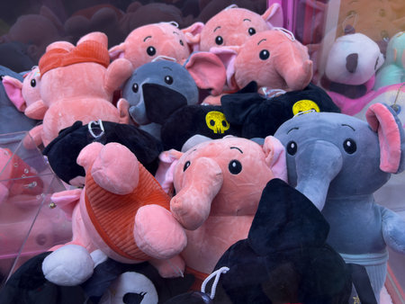 A bunch of stuffed animals, including elephants, pigs, and elephants with hats, are displayed in a storeの写真素材