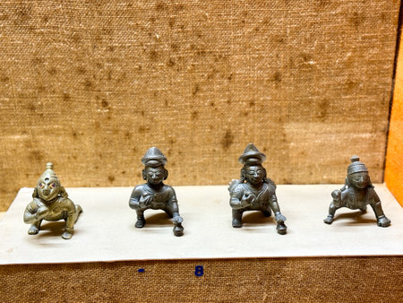 Four statues of Indian gods are displayed on a table. The statues are all different sizes and are made of metal. The table is covered with a cloth and the statues are arranged in a rowの写真素材