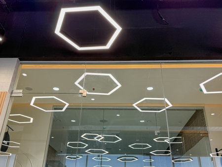 A building with a lot of hexagonal lights on the ceiling. The lights are white and are evenly spaced