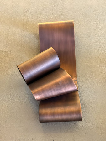 Three pieces of metal art are hanging on a wall. The art is made of copper and has a unique,...