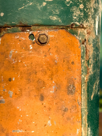 A rusty metal pole with a green and orange tag on it.