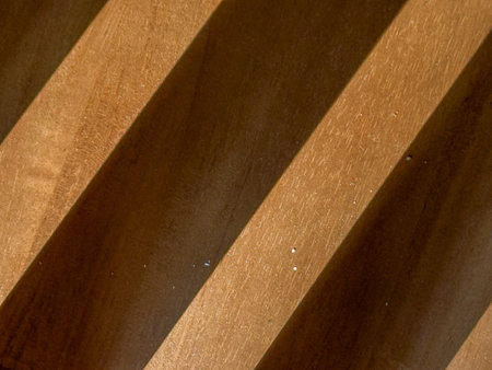 A wooden surface with a striped pattern. The wood appears to be of a darker color, and the stripes are visible on the surface. Scene is warm and inviting, as the wood grainの写真素材
