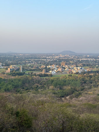A city with a mountain in the background. The sky is blue and the sun is setting. The city is full of buildings and housesの写真素材