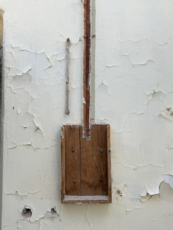 A wooden box is leaning against a wall with a hole in it. The box is old and worn, and the wall is covered in peeling paint. The scene gives off a sense of abandonment and neglectの写真素材