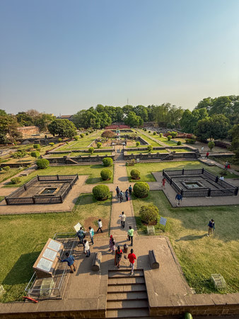 A large park with a lot of people walking around. The park is filled with trees and grass, and there are several benches and steps throughout the area. The atmosphere is lively and inviting, Shaniwar Wada Pune.の写真素材