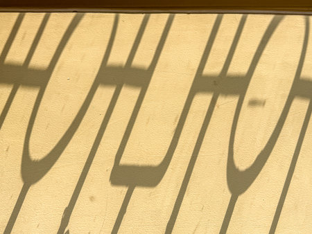 A shadow of a letter H on a concrete floor. The shadow is large and extends across the floor,...