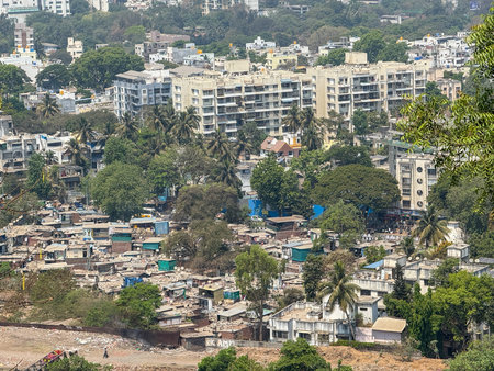 A cityscape with a large apartment building in the background. Concept of urban life and the contrast between the tall apartment building and the small, crowded housesの写真素材