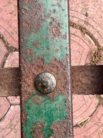 A rusted metal object with a green spot on it. The green spot is likely rust, which has formed on...