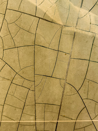 The image is a close up of a cracked and broken tile. The tile is made of a material that has a rough and uneven texture, giving it a worn and aged appearanceの写真素材