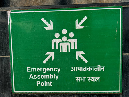 A green sign with a white arrow pointing to the right and the words "Emergency Assembly Point" written in redの写真素材