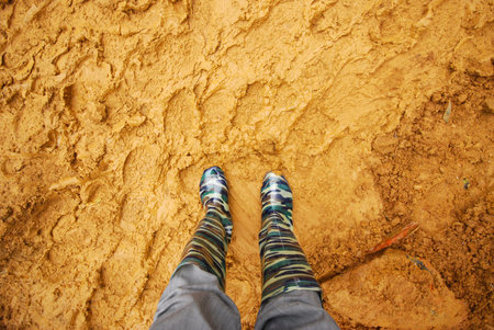 Leg in boot with dirty soil, muddy