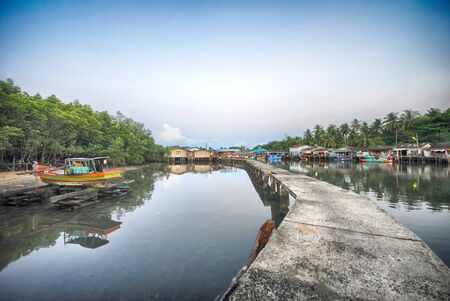 Bridge over the river among the floating house and fishery boat on the river in fishery village in Ban Mai Rood, Trat province, Thailandの写真素材