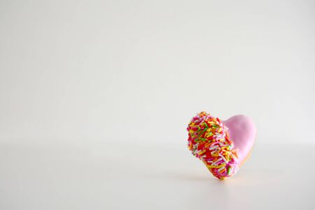 Heart shape of donut covered by pink chocolate rainbow sprinkle decoration on isolate,Valentine dayの写真素材