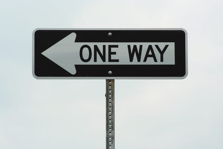 One way sign against cloudy sky