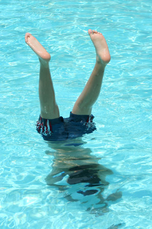 A Teenage boy doing a handstand in a pool