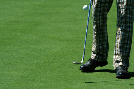 Golfer juggling a golf ball with retro pants