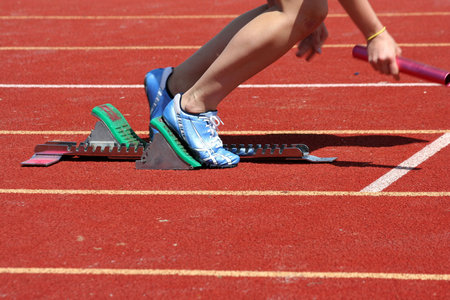Runner leaving starting blocks with baton