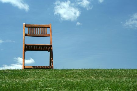 A Wooden chair with grass and skyの写真素材