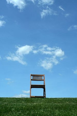 A Wooden chair with grass and skyの写真素材
