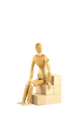 A Wooden manikin sitting on blocksの写真素材