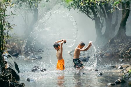 two boys are playing water at river.の写真素材