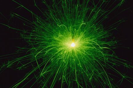 Green sparkler on black ideal background for festivities  の写真素材