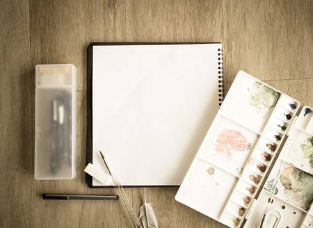 Top view of notebook and artist color palette on wood floor vintage picture styleの写真素材