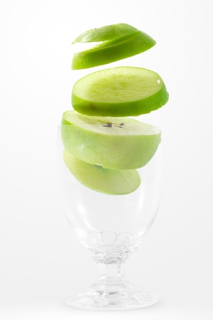 Slices of green apple falling into a glass の写真素材