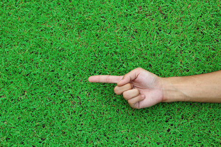 Human hand point with finger on green grass background texture