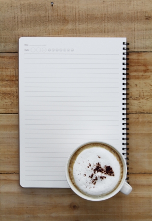 Cup of coffee and notebook paper on a wooden tableの写真素材
