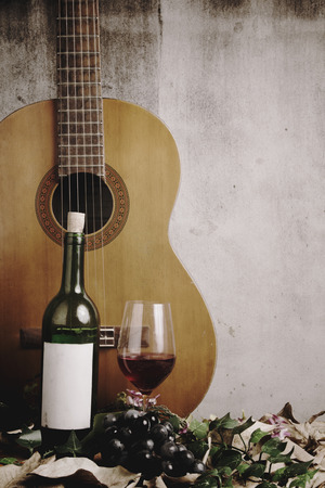 Still life of red wine bottle and wine glass with acoustic guitarの写真素材