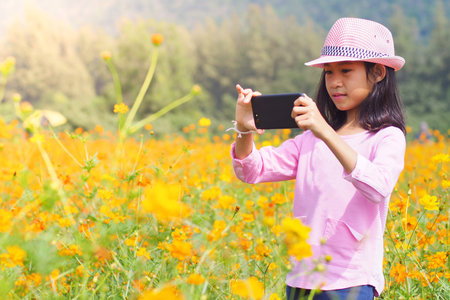 Girl taking photo mobile phones in flowers fieldの写真素材