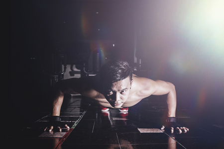 Asian young man push up in gym, Dark lighting low key with lens flare conceptの写真素材