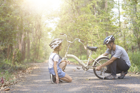 Happy father helped his daughter repair the bike, togetherness relaxation conceptの写真素材