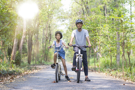Happy father and daughter cycling in the park, togetherness relaxation conceptの写真素材