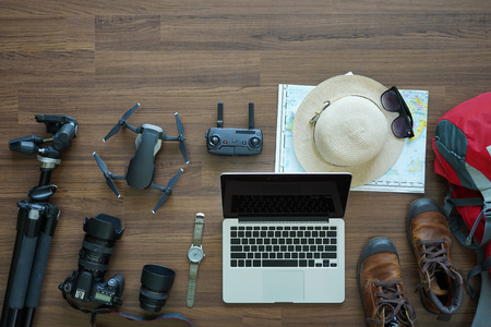 Overhead view of Traveler's accessories, trip vacation, tourism mockup, Laptop computer, camera, drone, bag, shoes with map on wooden table background, top viewの写真素材
