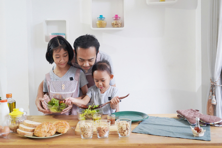 Father and his daughters cooking in the kitchen at home, happy family Asian conceptの写真素材