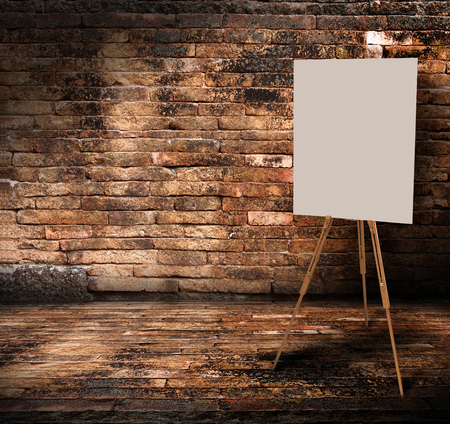 Wooden easel with mock up empty blank canvas stand in brick wall roomの写真素材