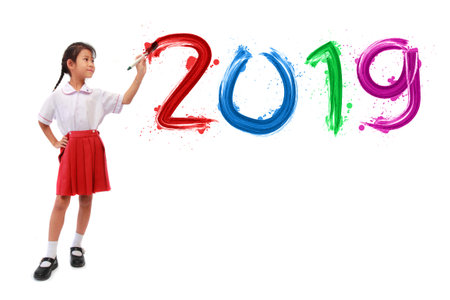 Little girl holding a paint brush painting happy new year 2019 on a white wall background, Back to...
