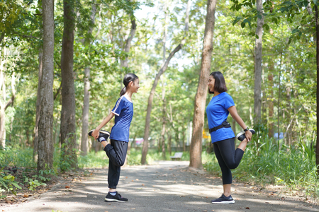Asian mother and daughter warm up stretch thigh muscles before running at the parkの写真素材