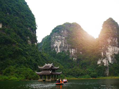 The boat that was paddling along the waterway with high mountains in Halongbok, Vietnamの写真素材