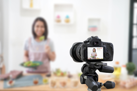 Asian woman making a Vlog video digital camera for her blog cooking in the kitchen room.の写真素材